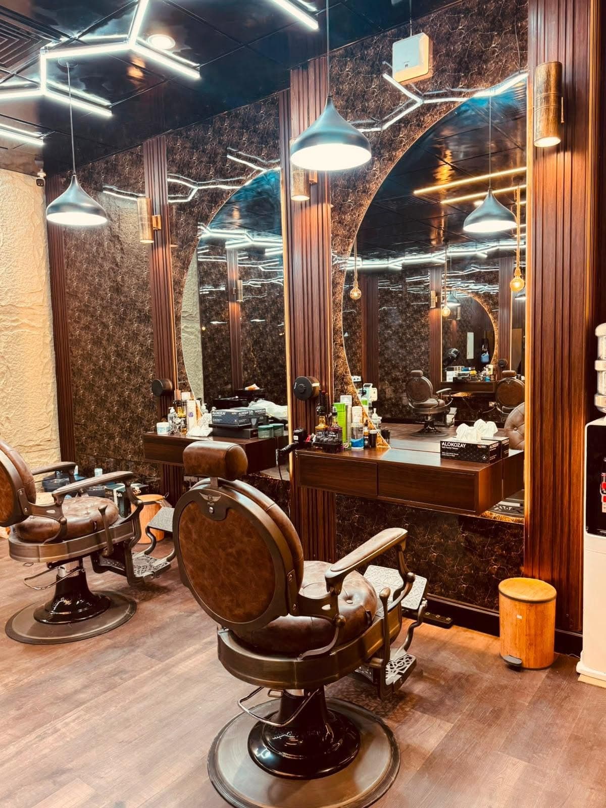 Two cognac leather barber chairs facing arched mirrors